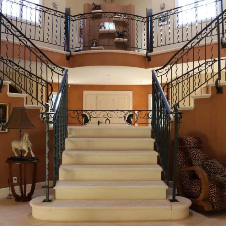départ escalier demi rond dans une entrée avec fer forgé
