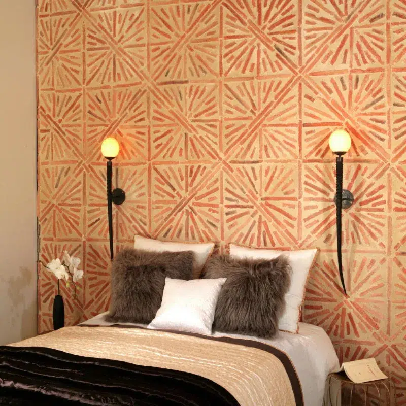 Chambre avec un lit et deux lampes de chevet. Mur en brique derrière le lit.