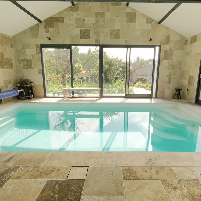 carrelage travertin choix naturel au bord d'une piscine couverte