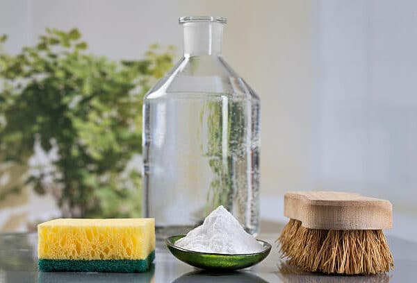 brosse a poils, avec du bicarbonate de soude en poudre et du vinaigre, pour nettoyer un mur en parement pierre